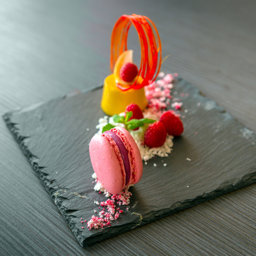 An artistic dessert presentation featuring a pink macaron and fresh berries at the Elements of the Soul Retreat by Eclectic Lyfe LLC